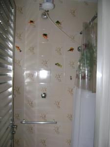 a bathroom with a shower with a white tiled wall at Apartamento Temporada Enseada in Guarujá