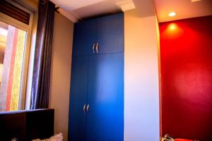 a room with blue cabinets and a red wall at Luxury Studio Apartment in Kampala