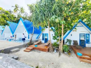 a row of blue and white houses with trees at Tria Maria Cottage in Ngurblut