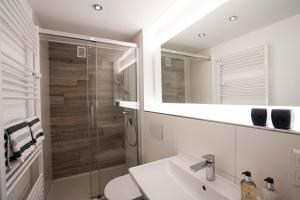une salle de bain avec une douche, un lavabo et un miroir dans l'établissement Strand Koje, à Westerland 15 autres photos