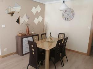 a dining room table with chairs and a clock on the wall at El piso de Amalia in Casalarreina