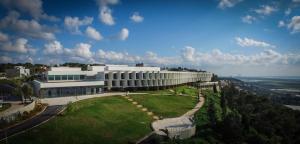 兹奇隆亚科夫Elma Hotel and Art Complex的一座白色的大建筑,前面有一个绿色的草坪