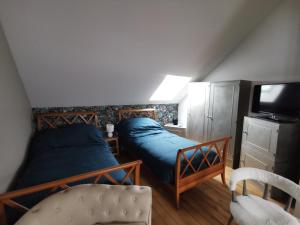 a bedroom with two beds and a tv and a chair at Domaine de la Dolce Vita de Gaudreville la rivière in Gaudreville-la-Rivière