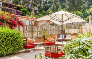 a patio with tables and chairs and an umbrella at Villa Sainte Anne in Porquerolles