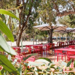 a group of red tables and chairs with umbrellas at Villa Sainte Anne in Porquerolles