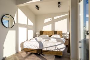 a bedroom with a bed with white sheets and a mirror at Vakantiewoning aan het water - met dakterras en balkon - Vista Maris - Nr 48 in Sint Annaland
