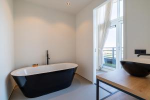 a black and white bathroom with a tub and a sink at Vakantiewoning aan het water - met dakterras en balkon - Vista Maris - Nr 48 in Sint Annaland