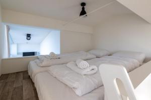 a room with four white beds with towels on them at Vakantiewoning aan het water - met dakterras en balkon - Vista Maris - Nr 48 in Sint Annaland