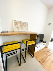 zwei gelbe Hocker stehen unter einem Schreibtisch in einem Zimmer in der Unterkunft Brko 7 in Jahorina + 13 Fotos