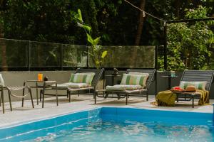 a swimming pool with chairs and a table next to a pool at Minimalist Panjim in Panaji