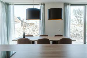 comedor con mesa, sillas y 2 luces en Vakantiehuis 6 persoons luxe, en Ouddorp