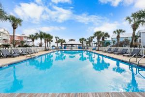 a large swimming pool with chairs and palm trees at Calypso Breeze in Gulf Shores