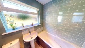 a bathroom with a sink and a tub and a window at Croyde Broadlands 5 Bedrooms in Croyde +21 photos
