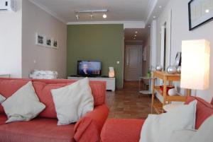 a living room with a red couch and a tv at Carabeo 24 Apartments Casasol in Nerja