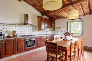 a kitchen with a wooden table and some chairs at Villa Il Poggio in Greve in Chianti