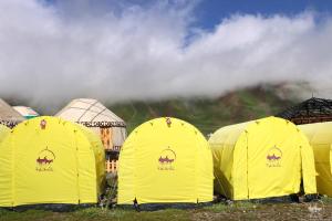 a group of yellow tents in a field at Yurt Glamping Edelweiss Meadow at the foot of Lenin Peak in Sary-Mogul