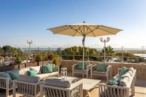 a patio with tables and chairs and an umbrella at Hotel Quinta do Lago in Quinta do Lago