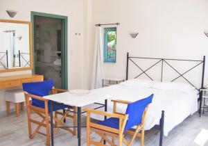 a bedroom with a white bed and blue chairs at Hotel Plakures in Falasarna