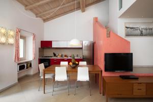 a kitchen with a wooden table and white chairs at La Rosa Del Mare in La Maddalena