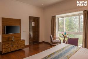 a bedroom with a bed and a tv and a window at StayVista at Pineview @ Albert Estate in Mussoorie