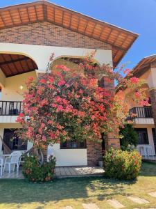 a large flowering tree in front of a building at Casa de Praia com vista mar e Foz do rio in Aquiraz