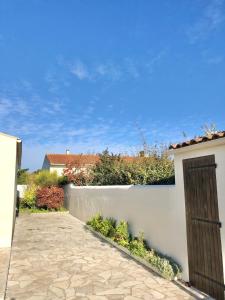 a white wall with a gate and a driveway at Maison familiale 3 chambres proche de la plage, jardin & tranquillité in Saint-Denis-dʼOléron +6 photos