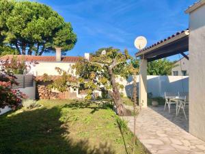 a garden with a tree in the middle of a yard at Maison familiale 3 chambres proche de la plage, jardin & tranquillité in Saint-Denis-dʼOléron