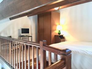 a bedroom with a staircase with a bed and a television at Maison familiale 3 chambres proche de la plage, jardin & tranquillité in Saint-Denis-dʼOléron