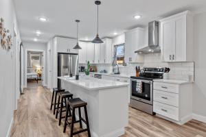 a kitchen with white cabinets and an island with bar stools at 4456 Blue Door Bungalow in Southhampton