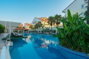 a pool at a resort with palm trees and buildings at Sural Resort Hotel in Side