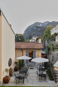 a patio with tables and umbrellas in front of a building at Villa Issima "The Bellagio Suite" - Menaggio by LoveComo in Menaggio