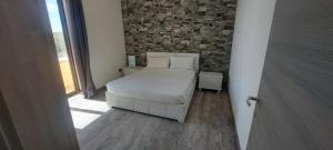 a bedroom with a white bed and a brick wall at Casa al Castello in Portopalo