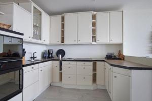 - une cuisine blanche avec des armoires blanches et des appareils noirs dans l'établissement Sterflat 199, à Egmond aan Zee