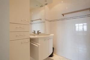 une salle de bain blanche avec lavabo et douche dans l'établissement Sterflat 199, à Egmond aan Zee 28 autres photos