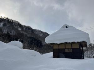 einen schneebedeckten kleinen Schuppen vor einem Berg in der Unterkunft 鬼無里の湯 ホテル&コテージ in Nagano