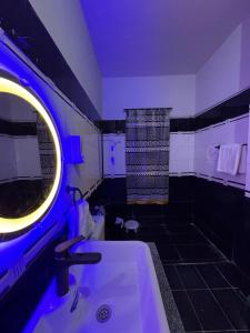 a bathroom with a white sink and a blue light at Rosewood Cottage in Karachi