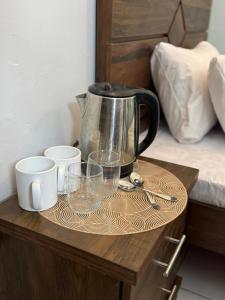 - une cafetière sur une table en bois avec des verres dans l'établissement Rosewood Cottage, à Karachi