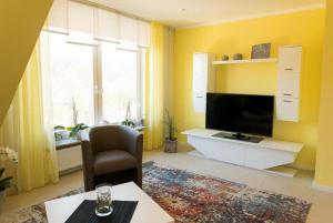 a yellow living room with a television and a chair at Apartment Wallberg "Nest" in Detmold