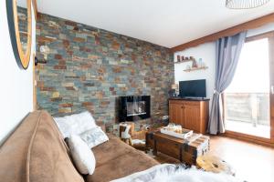a living room with a couch and a brick wall at Appartement pour 6, 700m des pistes de ski in La Joue du Loup
