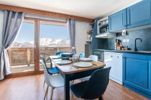 a kitchen with blue cabinets and a table with chairs at Appartement pour 6, 700m des pistes de ski in La Joue du Loup