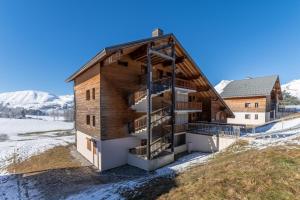 a wooden house with a balcony in the snow at Appartement pour 6, 700m des pistes de ski in La Joue du Loup