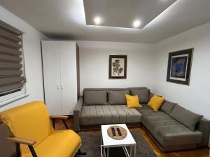 een woonkamer met een grijze bank en gele stoelen bij Martina Lux in Belgrado