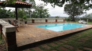 a swimming pool with a patio and an umbrella at Chácara Samambaia Piracicaba in Piracicaba
