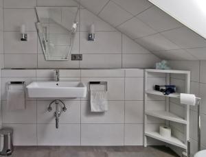 ein weißes Badezimmer mit Waschbecken und Spiegel in der Unterkunft Ferienwohnungen Vesteblick in Dörfles