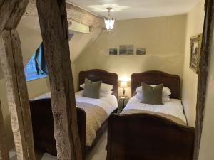 two twin beds in a room with two windows at Broughwood Cottage Snowshill in Broadway