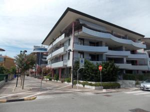 a large apartment building on a street with a parking lot at Costa Azzurra Apartment in Grado