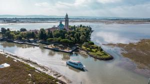 an island with a boat in a river with a church at Costa Azzurra Apartment in Grado +2 photos