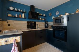 a blue kitchen with a sink and a microwave at Le Quincy - Maison à 10km de Disneyland in Quincy-Voisins +7 photos
