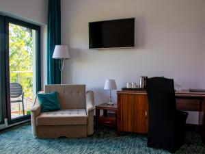 a room with a chair and a desk and a television at Hotel Sobieraj in Krzeszyce