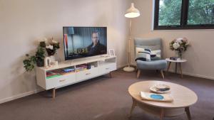 a living room with a flat screen tv and a chair at Cosy getaway in the Heart of Braddon - Hosted by Canstay in Canberra